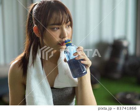 Tired sporty girl taking a rest and drinking a water Tired sporty girl taking a rest and drinking a water 83741866