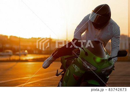 Cool man on motorcycle against sundown sky Cool man on motorcycle against sundown sky 83742673