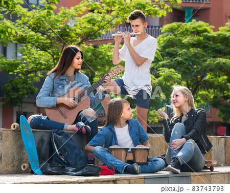 Portrait of four teenagers playing music together outdoors Portrait of four teenagers playing music together outdoors 83743793