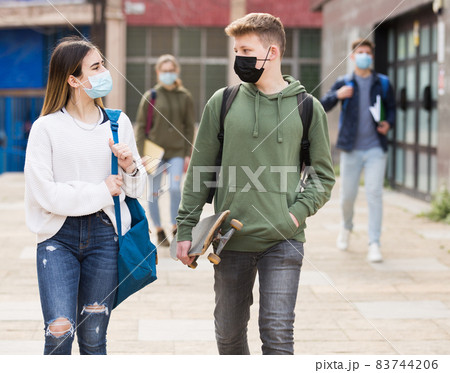 Guy and girl in protective masks are walking carelessly down street 83744206
