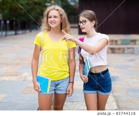 Two positive girlfriends walking down street to college 83744318