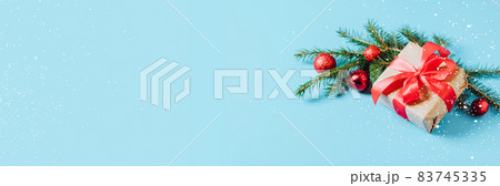 Festive box with a red bow on a blue background with Christmas toys balls branch of fluffy spruce sparkles and confetti . New Year Christmas concept. Flat festive mockup with copy space Festive box with a red bow on a blue background with Christmas toys balls branch of fluffy spruce sparkles and confetti . New Year Christmas concept. Flat festive mockup with copy space 83745335