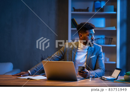 Young african american businessman working indoors in office at night. 83751949