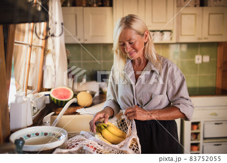 Happy senior woman unpacking shopping indoors at home, sustainable lifestyle. 83752055