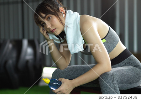 Beautiful and sweaty fitness woman tired after workout, take a rest in the gym. 83752438