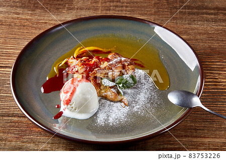 Apple strudel with mint and ball of vanilla ice cream on dish on a wooden background. All sprinkled with powdered sugar. 83753226