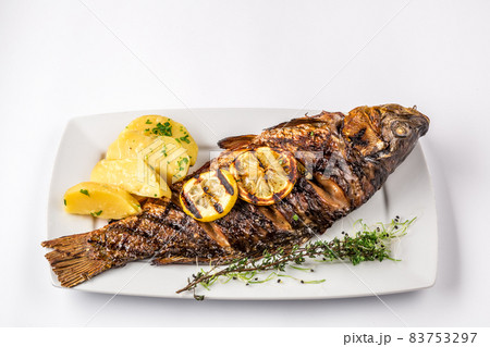 Grilled carp fish with rosemary potatoes and lemon, close up Grilled carp fish with rosemary potatoes and lemon, close up 83753297