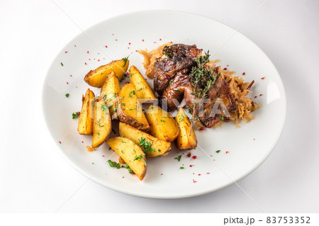 Delicious grilled duck wings with potatoes and stewed cabbage on a white plate Delicious grilled duck wings with potatoes and stewed cabbage on a white plate 83753352