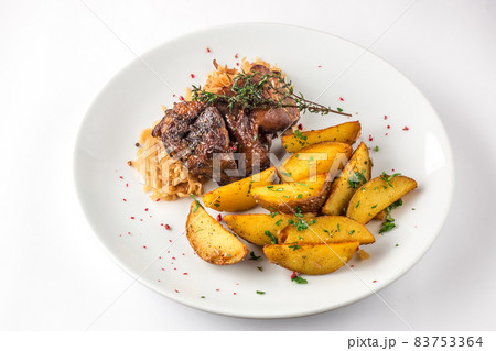 Delicious grilled duck wings with potatoes and stewed cabbage on a white plate Delicious grilled duck wings with potatoes and stewed cabbage on a white plate 83753364