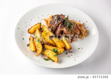 Delicious grilled duck wings with potatoes and stewed cabbage on a white plate 83753366