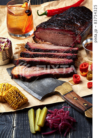 Fresh Brisket BBQ beef sliced for serving against a kraft paper background with sauce, hot peppers and corn. Fresh Brisket BBQ beef sliced for serving against a kraft paper background with sauce, hot peppers and corn. 83754325