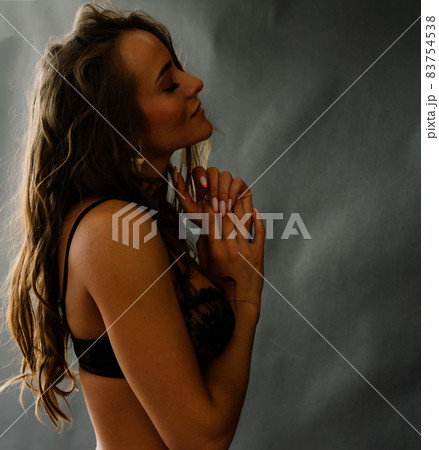 Seductive pose of dark haired woman wearing a black bikini 83754538