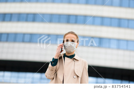 A young businesswoman wearing a health mask and talking on the phone in the city 83754541