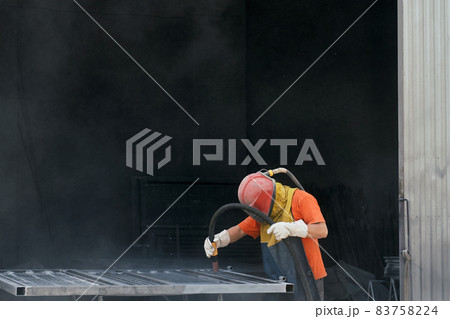 Worker using sandblaster for cleaning surface of metal  83758224