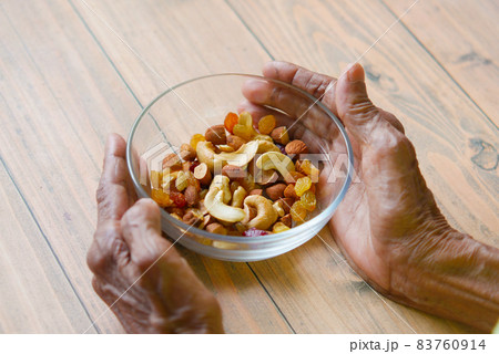 senior women hand hold a bowl of many mixed nuts  83760914