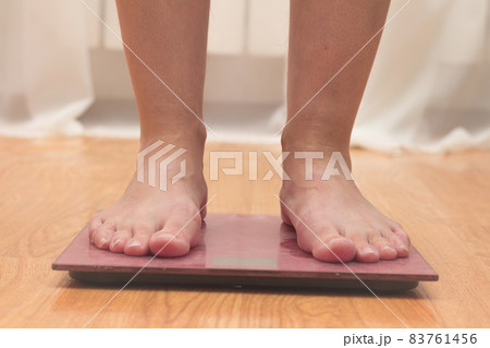 A woman is weighed on a household scale at home. A woman is weighed on a household scale at home. 83761456