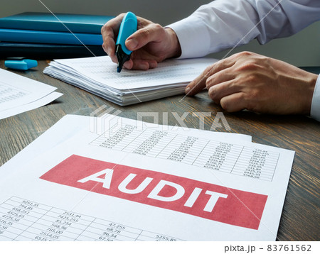 Audit report and working auditor with stack of papers. Audit report and working auditor with stack of papers. 83761562
