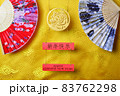 Gold tiger symbol and pair of chinese bamboo paper fans on yellow fabric with traditional chinese ornament with clouds. Chinese New Year of the Tiger 2022. Translation: happy new year 83762298