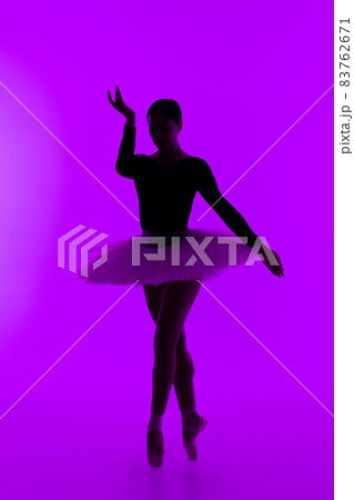 Beautiful ballerina on purple background dancing ballet. Woman performs smooth movements. Sensual 83762671