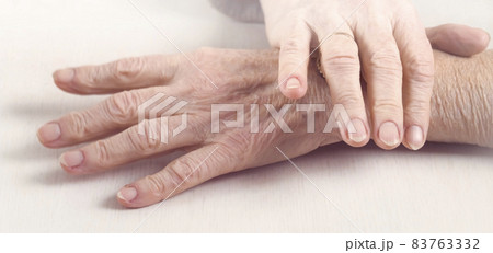 The hands of an elderly well-groomed woman in a casual sweater. 83763332