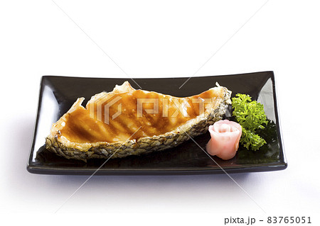 Grilled fish fillet steak with soy sauce on black dish on white background. Grilled fish fillet steak with soy sauce on black dish on white background. 83765051