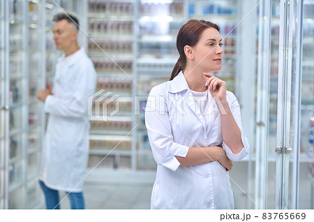 Pensive woman in uniform and employee at pharmacy 83765669