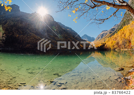 Mountain lake with crystal water and colorful autumnal trees. Mountains and lake in sunny day 83766422