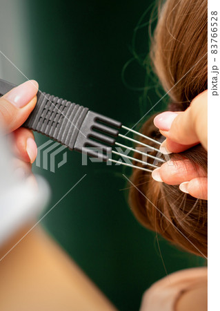 Close Up hairdresser stylist makes hairstyle for a young woman in a beauty salon. 83766528
