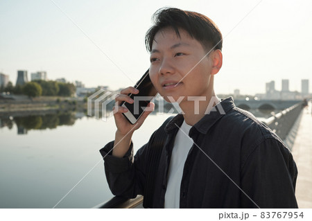 Pretty Chinese business agent with smartphone by her ear Pretty Chinese business agent with smartphone by her ear 83767954