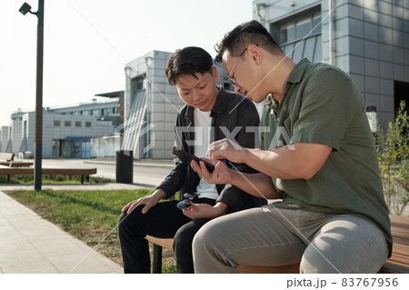 Two young chinese employees watching online video Two young chinese employees watching online video 83767956