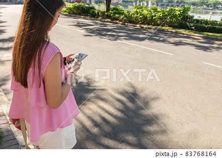 Young woman using smart phone outdoors in sunny morning Young woman using smart phone outdoors in sunny morning 83768164
