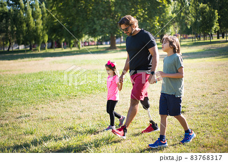Side view of father with disability walking with children 83768317