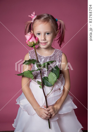 Little caucasian girl in a festive dress with sequins posing with rose flower 83768704