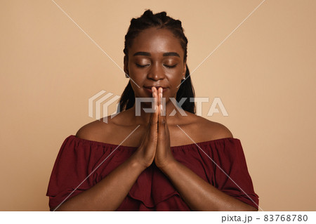 Delighted african american woman praying with closed eyes Delighted african american woman praying with closed eyes 83768780