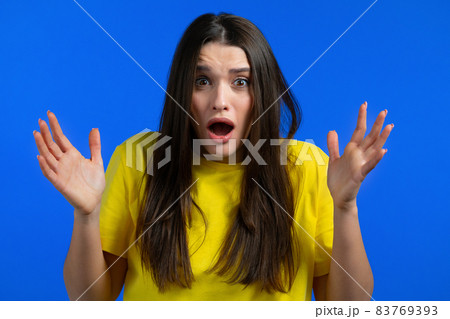 Portrait of unpleasantly surprised and shocked girl on blue studio background. Woman receiving bad 83769393