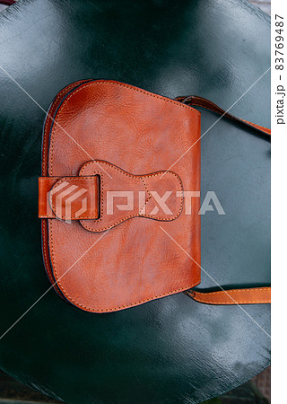 small orange women's leather bag on a green table small orange women's leather bag on a green table 83769487