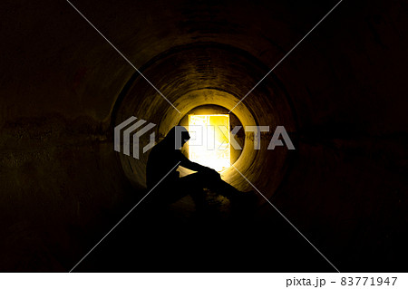 Man sitting in underground concrete tunnel Man sitting in underground concrete tunnel 83771947