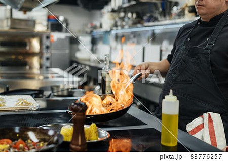 side view male chef flambeing dish. High quality beautiful photo concept 83776257