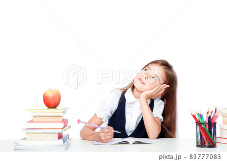 Cute little child girl looking up on the desk at school. 83777083