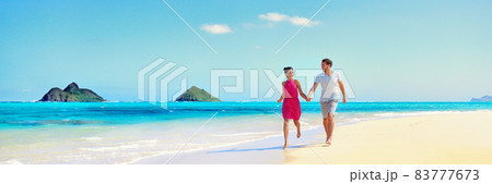 Hawaii vacation couple walking relaxing on white sand and pristine turquoise ocean water on Hawaiian beach Lanikai, Oahu island, USA. Holiday background with blue sky copy space for travel concept. 83777673