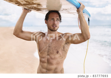 Sexy active watersport fitness abs man carrying his surfboard on the head. Surfer lifestyle on Hawaii beach during summer travel vacation. Caucasian athlete going out surfing holding surf board. 83777693