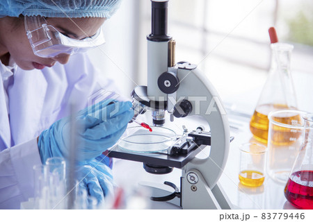 Closeup Woman scientist hand use dropper in lab look at science microscope medical test, research biology chemistry. Females technician laboratory analyzing blood scientific pharmaceutical research. 83779446