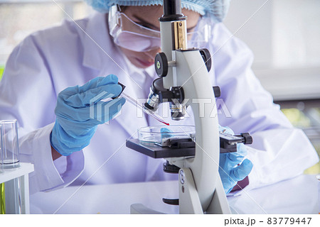 Closeup Woman scientist hand use dropper in lab look at science microscope medical test, research biology chemistry. Females technician laboratory analyzing blood scientific pharmaceutical research. 83779447