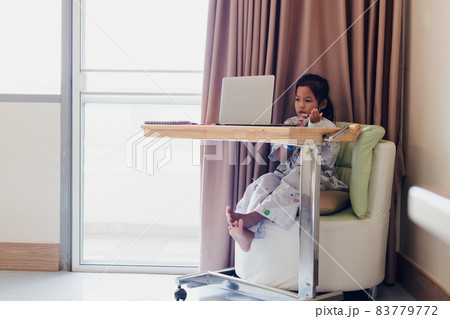 Sick asian child sitting and learning online class with teacher and friend while stay in private patient rooms in the hospital. Isolation homeschooling and distance learning. 83779772