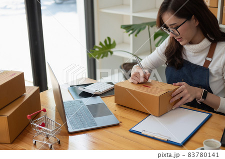 Starting Small business entrepreneur SME freelance,Portrait young woman working at home office, BOX,smartphone,laptop, online, marketing, packaging, delivery, SME, e-commerce concept. 83780141