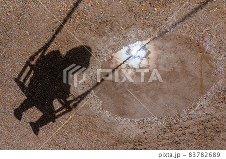 The shadow of a child on a swing. The sun is reflected in a puddle. Kid ride on a swing. Happy, carefree childhood The shadow of a child on a swing. The sun is reflected in a puddle. Kid ride on a swing. Happy, carefree childhood 83782689