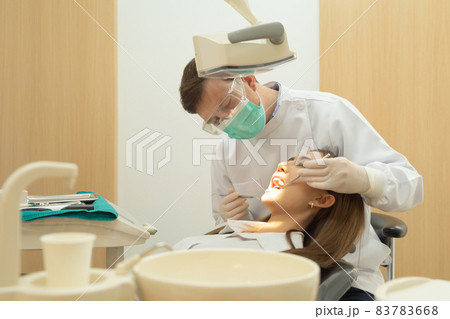 A dentist checking up Asian woman patient's teeth by using dental mouth mirror at hospital clinic. Teeth check up with dental tools. Doctor. Dentistry, medical and health. People. 83783668
