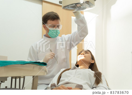 A dentist checking up Asian woman patient's teeth by using dental mouth mirror at hospital clinic. Teeth check up with dental tools. Doctor. Dentistry, medical and health. People. 83783670