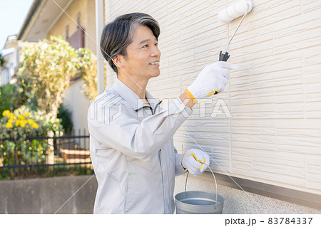 戸建ての壁をローラーで塗るペンキ職人 83784337