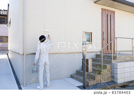 戸建ての壁をローラーで塗るペンキ職人 83784403